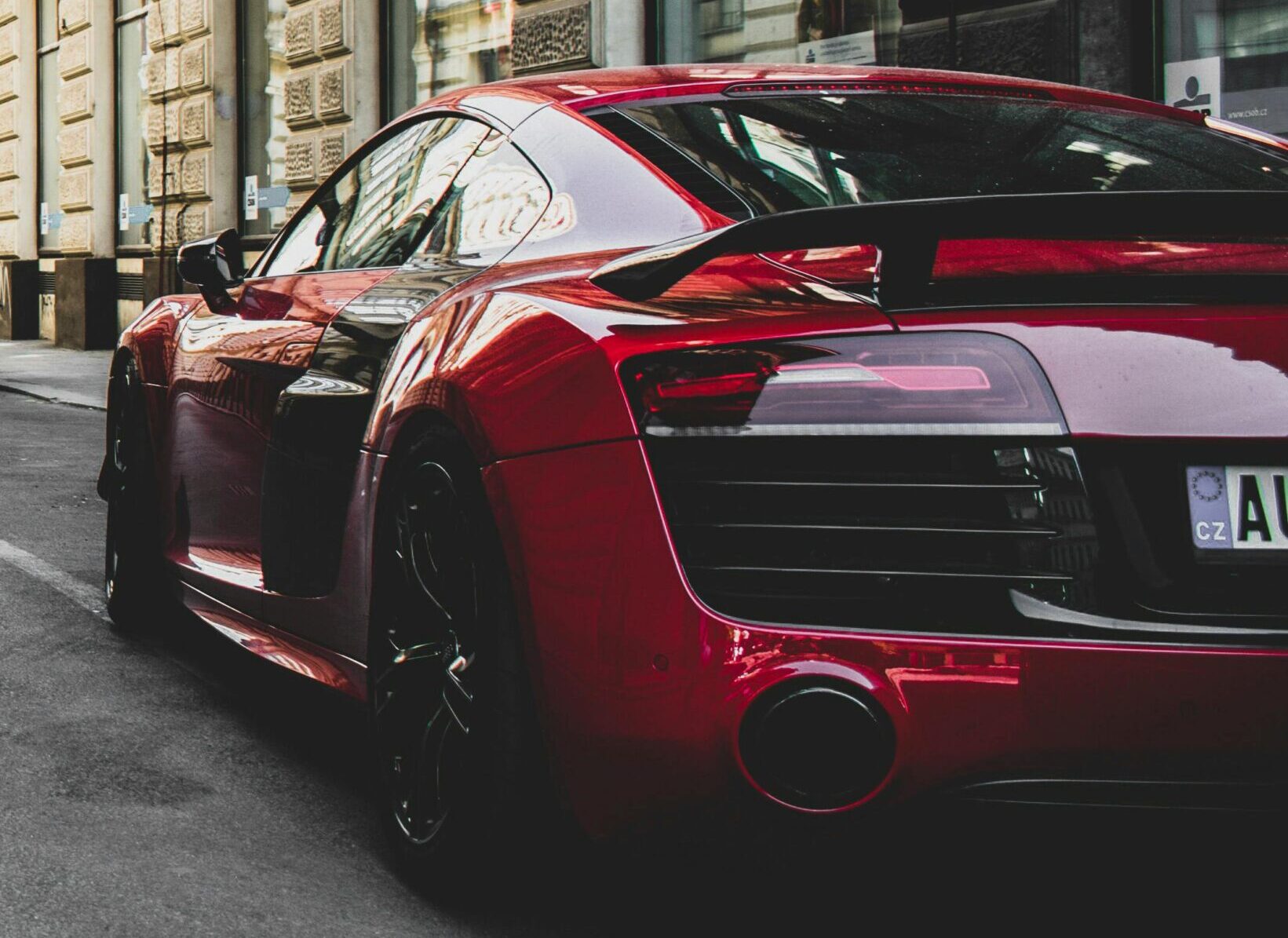 Red sports car parked on a city street with historic buildings.